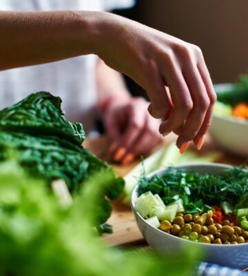 Person eating from a bowl of leafy vegetables