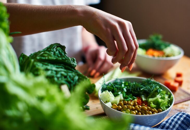 Person eating from a bowl of leafy vegetables