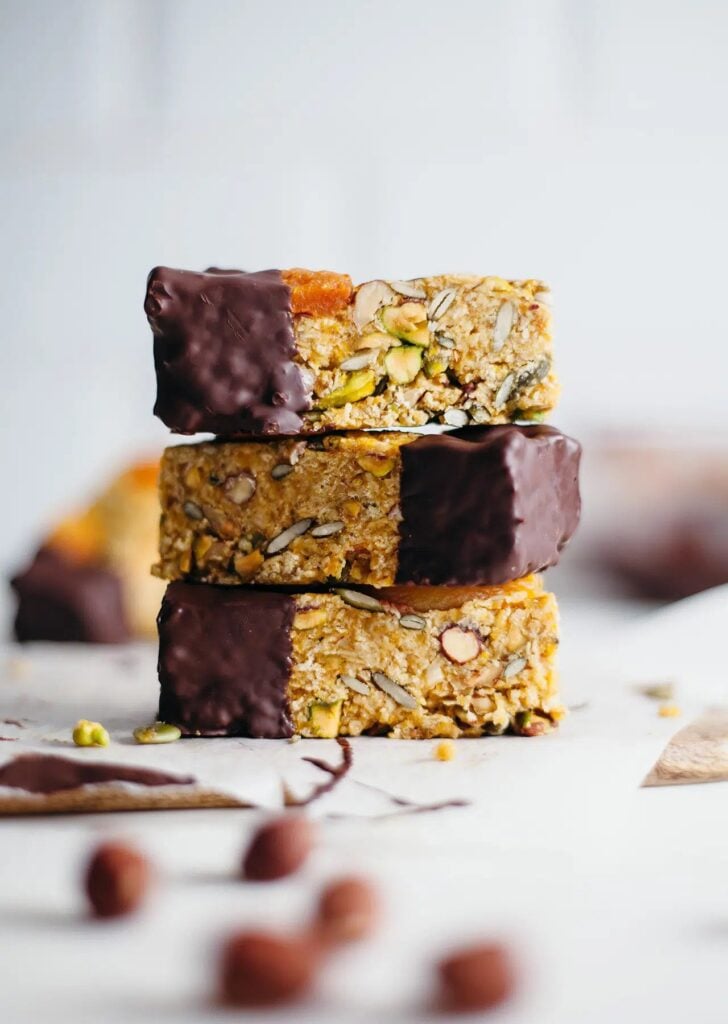 A stack of raw vegan apricot energy bars on a worktop with a white background