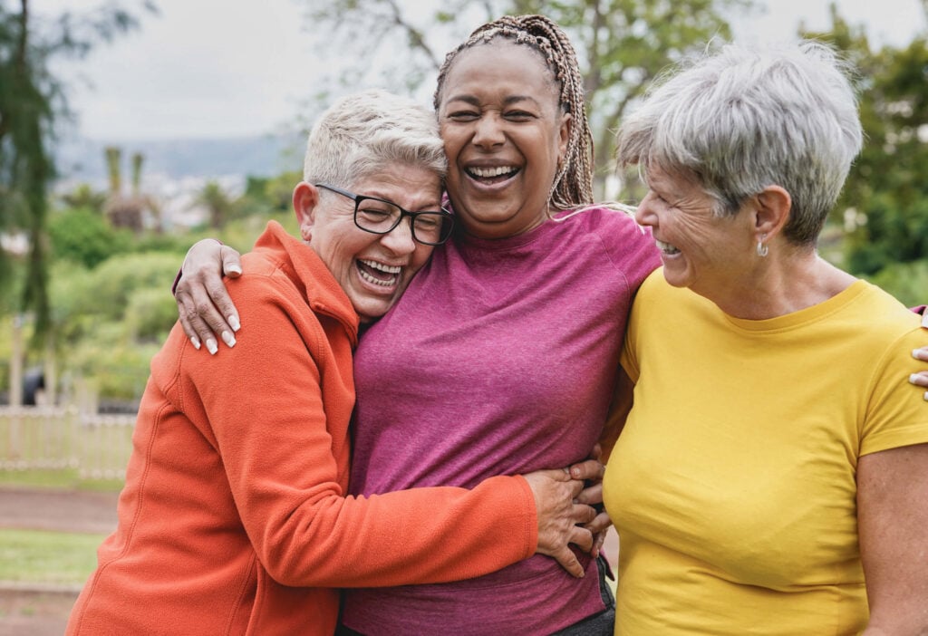 A group of older adults, who may be more vulnerable to vitamin B12 deficiency, laughing and hugging outdoors
