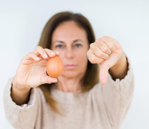 A woman holds an egg with a thumb down