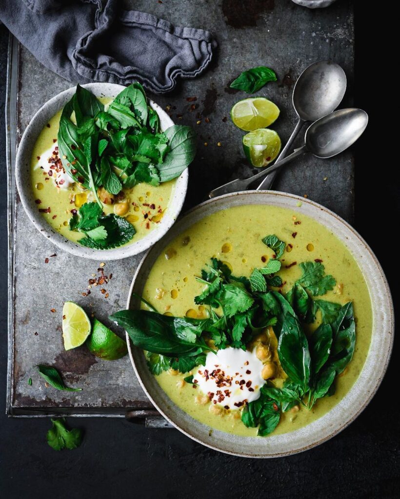 Two bowls of pretty green spiced chickpea stew served on a dark tray