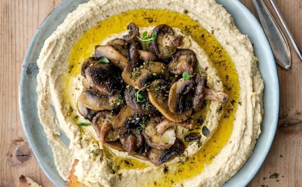 creamy mushroom vegan hummus presented in a stoneware bowl with crusty bread