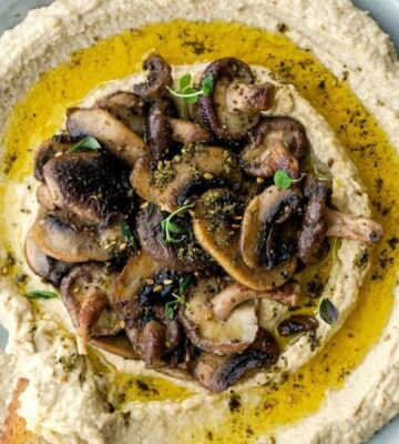 creamy mushroom vegan hummus presented in a stoneware bowl with crusty bread