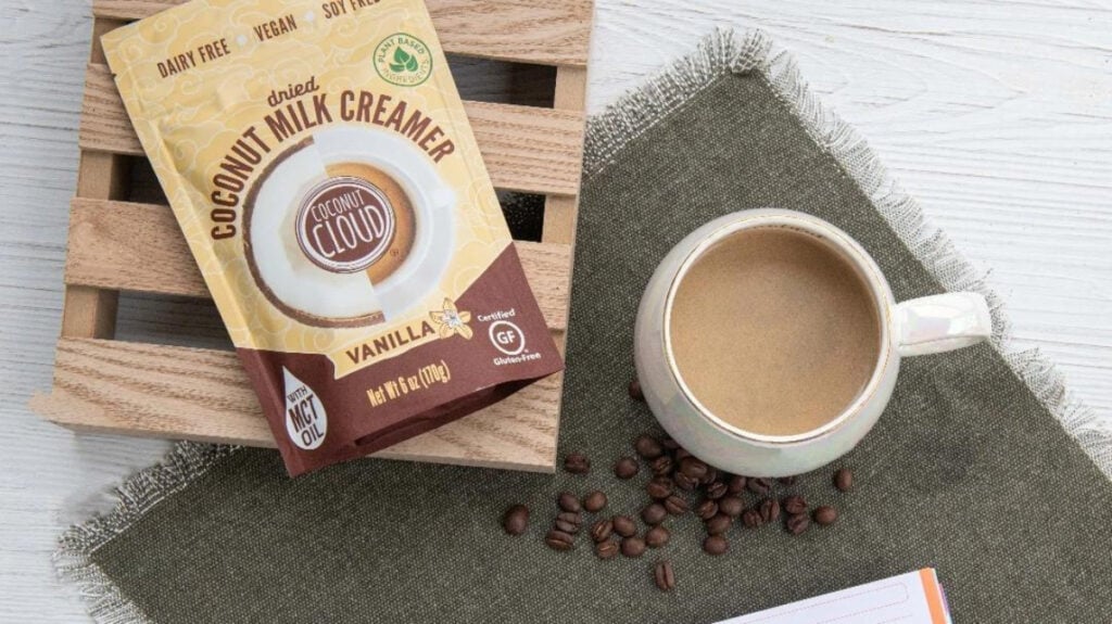 Dairy-free Coconut Cloud creamer beside a cup of coffee