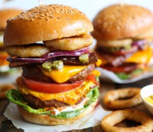 Viva Vegan Recipe Club's meat-free mega burger stacked with dairy-free cheese, salad, and onion rings