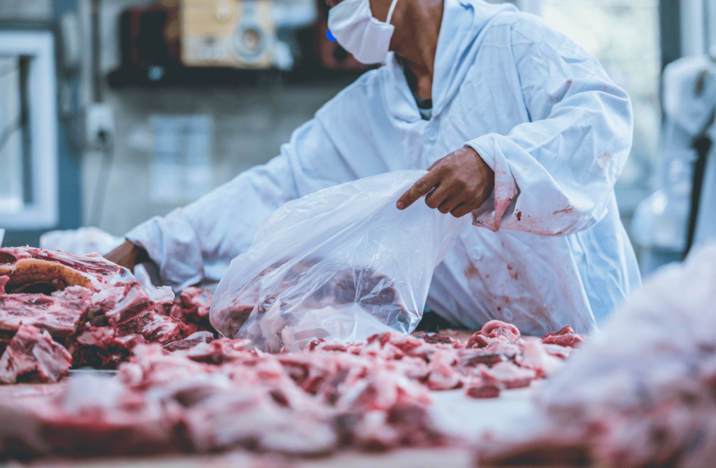 Meatpacking employees working on animal meat in a factory