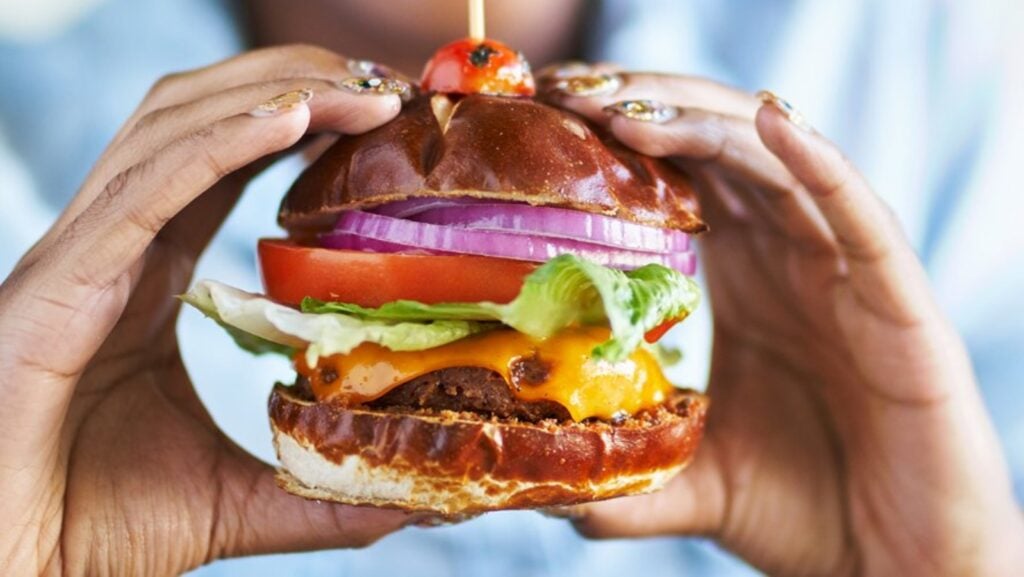 Two hands holding a cheeseburger