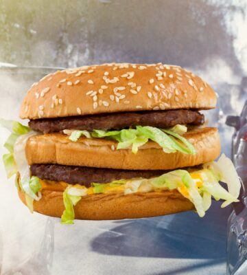 A McDonald's beef Big Mac burger in front of cars producing emissions