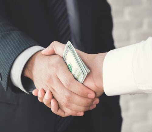 Businessmen handshake with money in hands