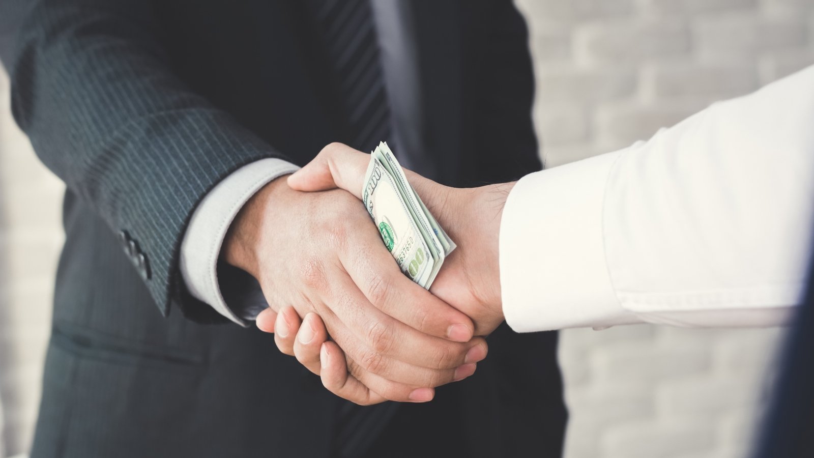 Businessmen handshake with money in hands