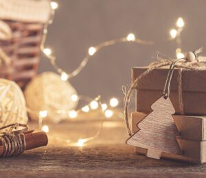 Cardboard Christmas gift boxes tied together with string with fairy lights in the background