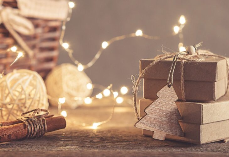 Cardboard Christmas gift boxes tied together with string with fairy lights in the background