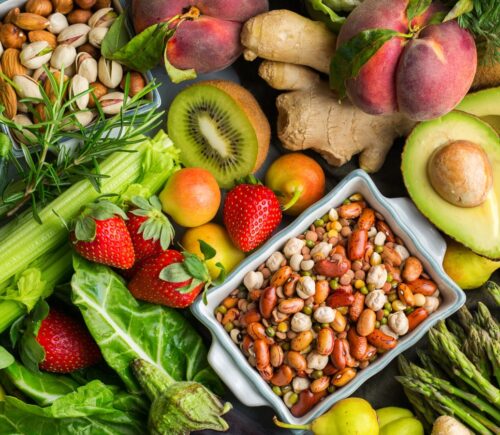 Overhead view table scene on a wooden background. Super food concept with green vegetables, berries, whole grains, seeds, spices and nutritious items.