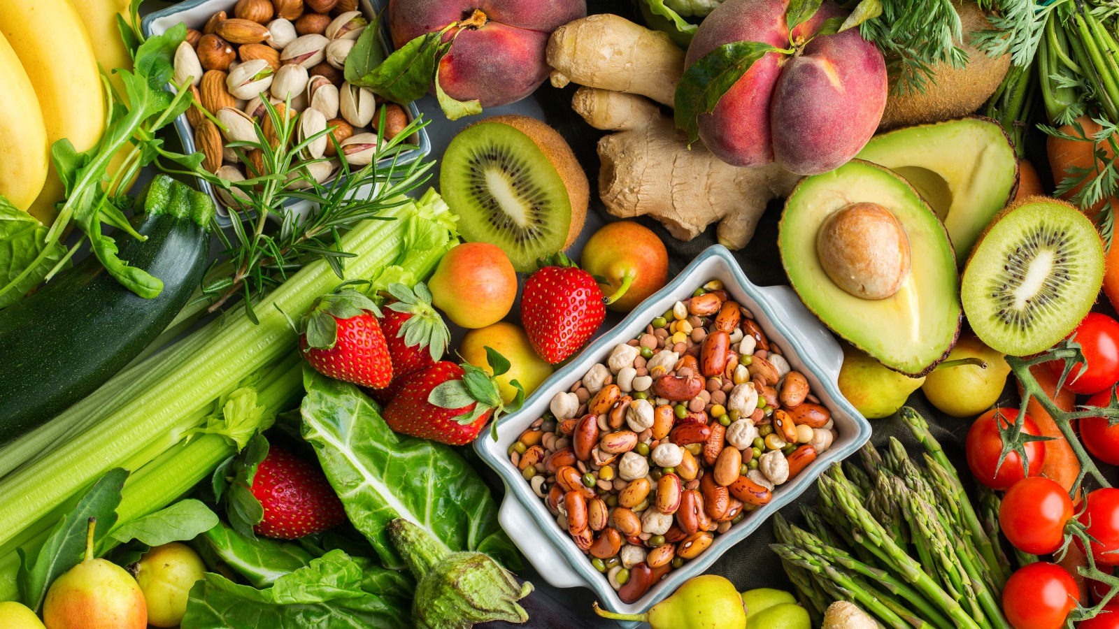 Overhead view table scene on a wooden background. Super food concept with green vegetables, berries, whole grains, seeds, spices and nutritious items.