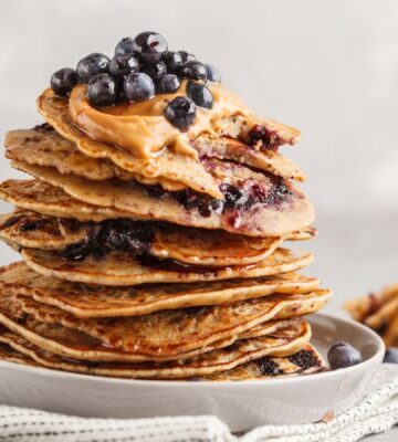a stack of vegan blueberry pancakes with peanut butter and syrup