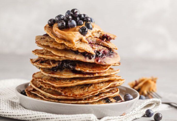 a stack of vegan blueberry pancakes with peanut butter and syrup
