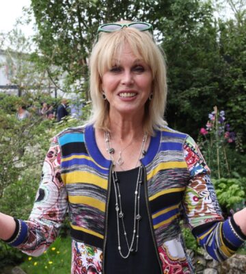 joanna lumley standing in a garden holding her arms out