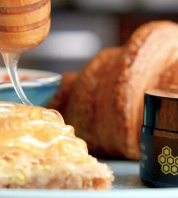 vegan honey spread over croissant using a honey dropper