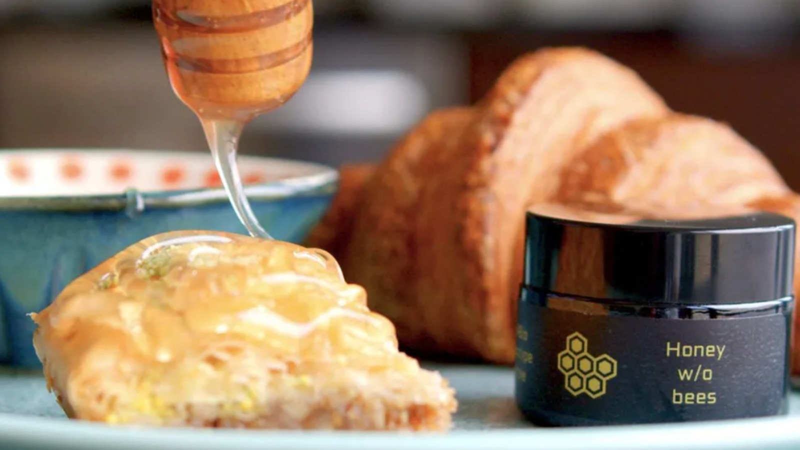 vegan honey spread over croissant using a honey dropper