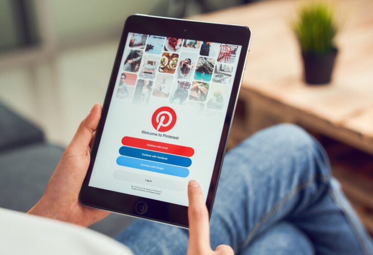A person holds a tablet showing the Pinterest log-in page