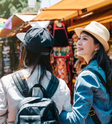 Two friends walking through an outdoor market