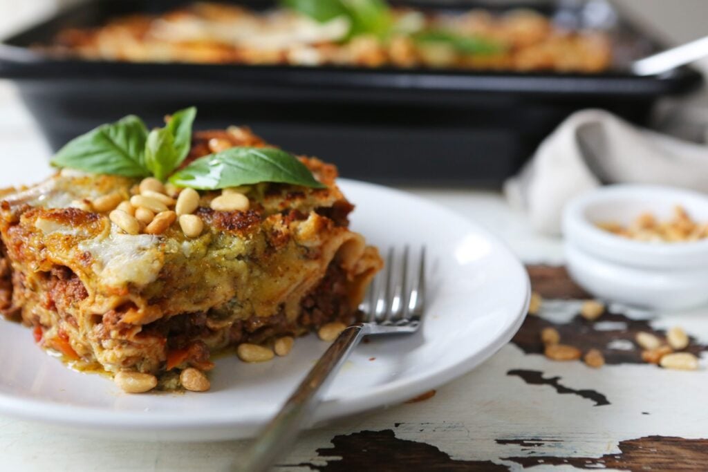 A portion of creamy vegan pesto cannelloni on a white plate, with a silver fork