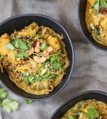 Three bowls of vegan spicy coconut noodles on a table