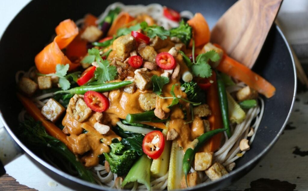 A frying pan of vegan stir fry with tahini, tofu, and vegetables