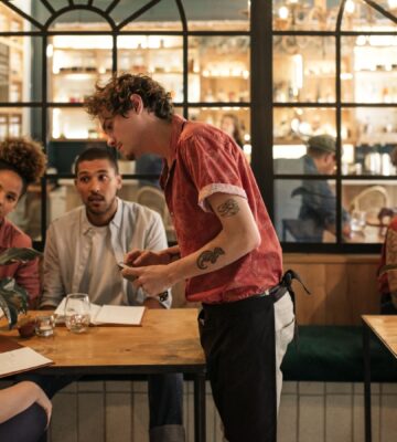 People sat at a table ordering food from menus