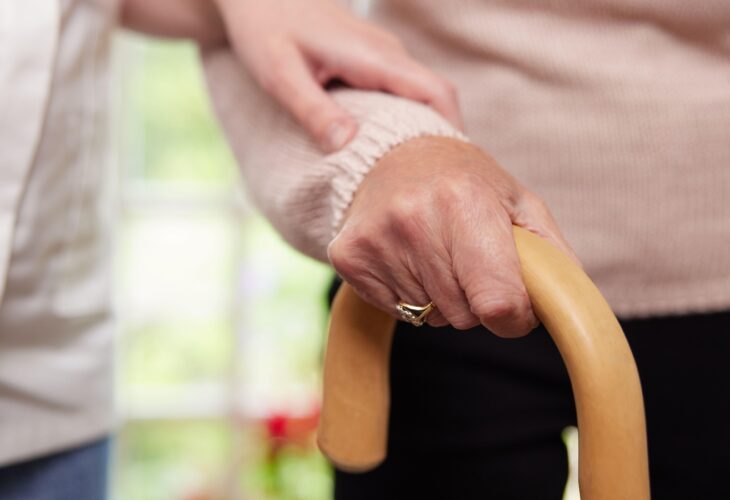 a person leans on a walking stick