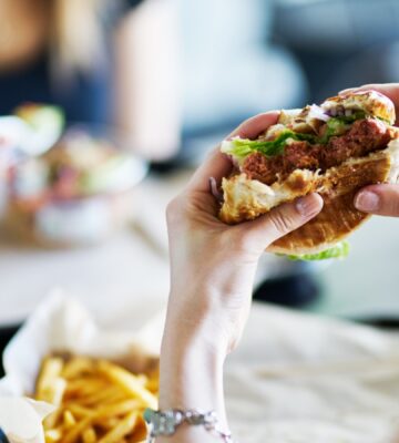 A person holding up a half eaten burger