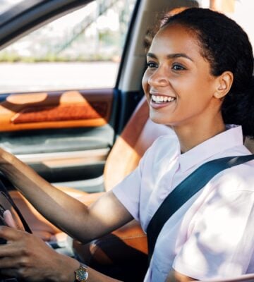 A woman smiling while she drives a car