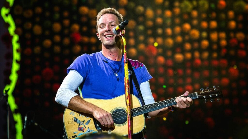 Chris Martin performs with guitar on stage