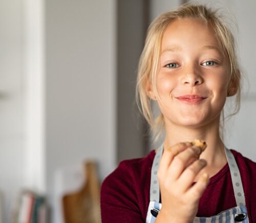 A young girl holds a piece of food