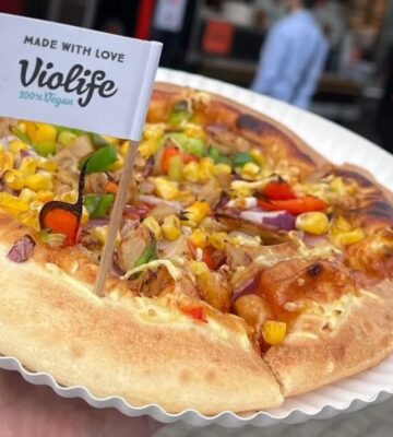 A pizza hut pizza with a Violife flag