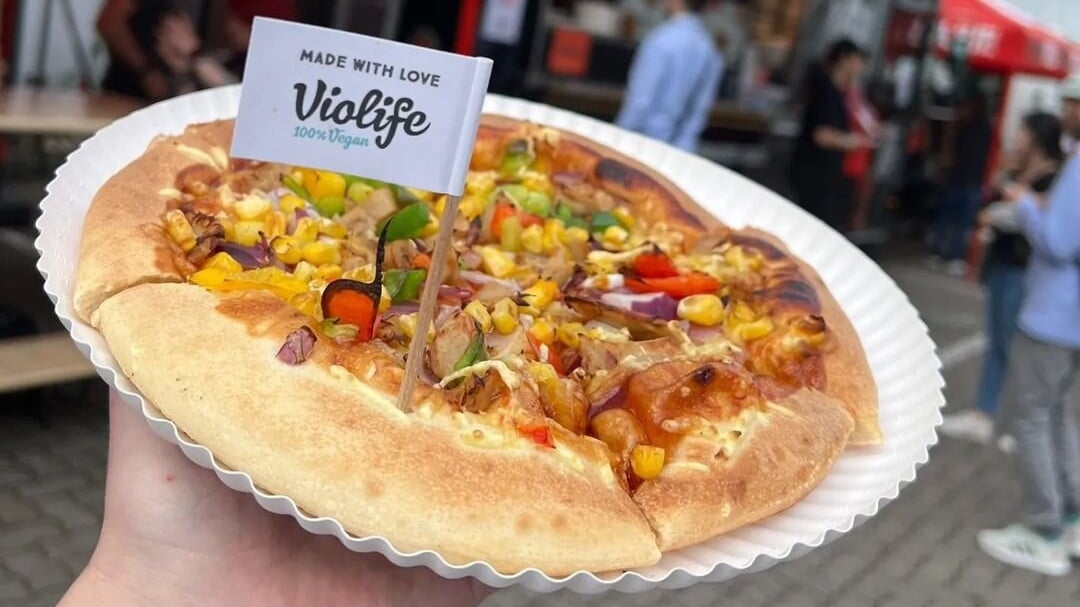 A pizza hut pizza with a Violife flag