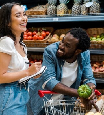 A couple laugh as they shop in the vegetable aisle