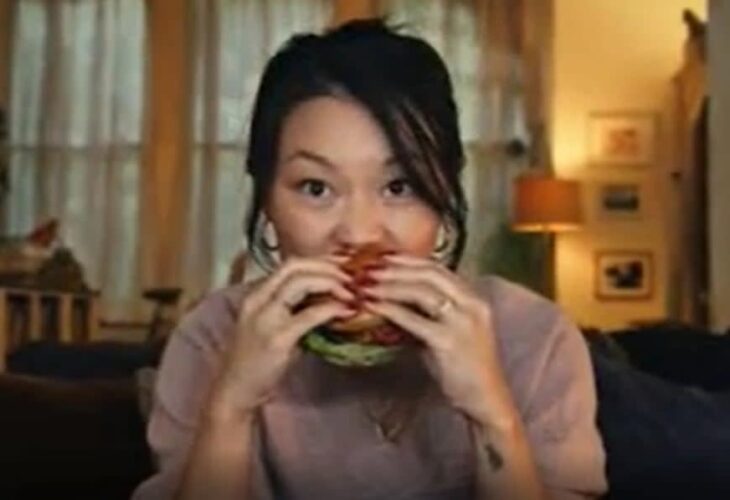 A still of Tesco's advert, a woman bites into a burger