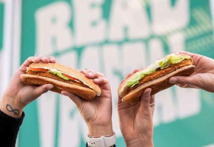Two people holding up plant-based burgers