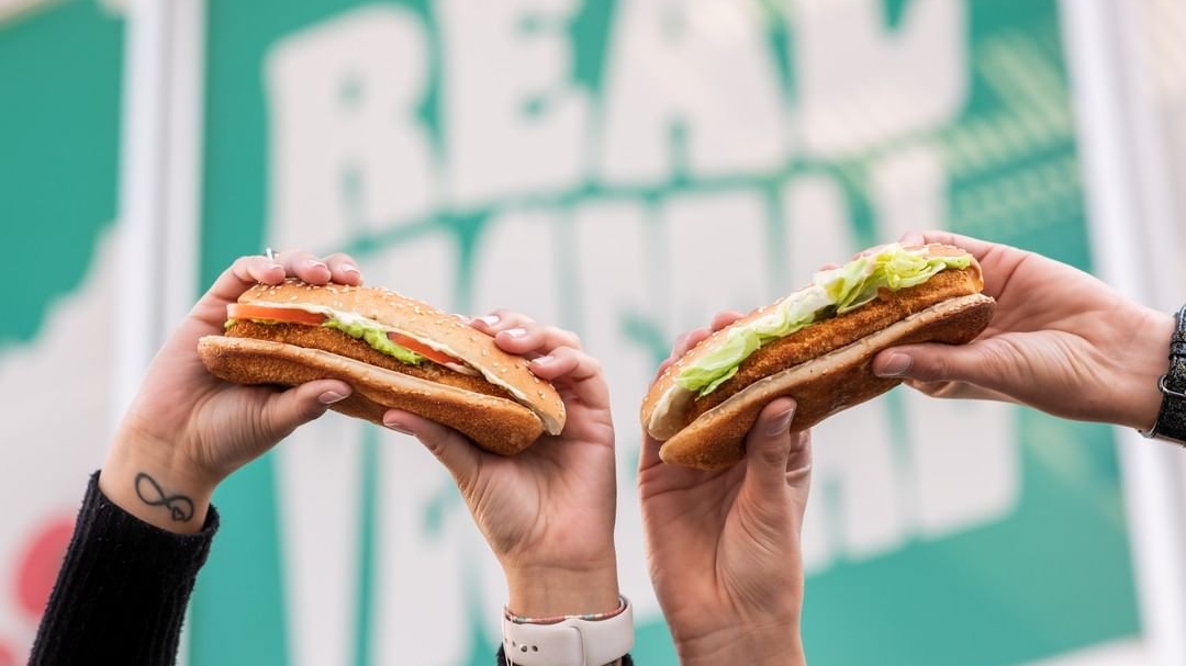 Two people holding up plant-based burgers