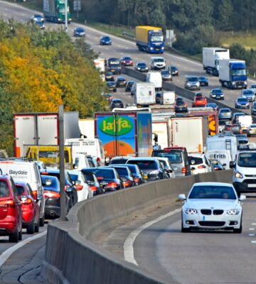 Rush hour on M25 UK motorway queue of cars trucks & lorries in traffic jam
