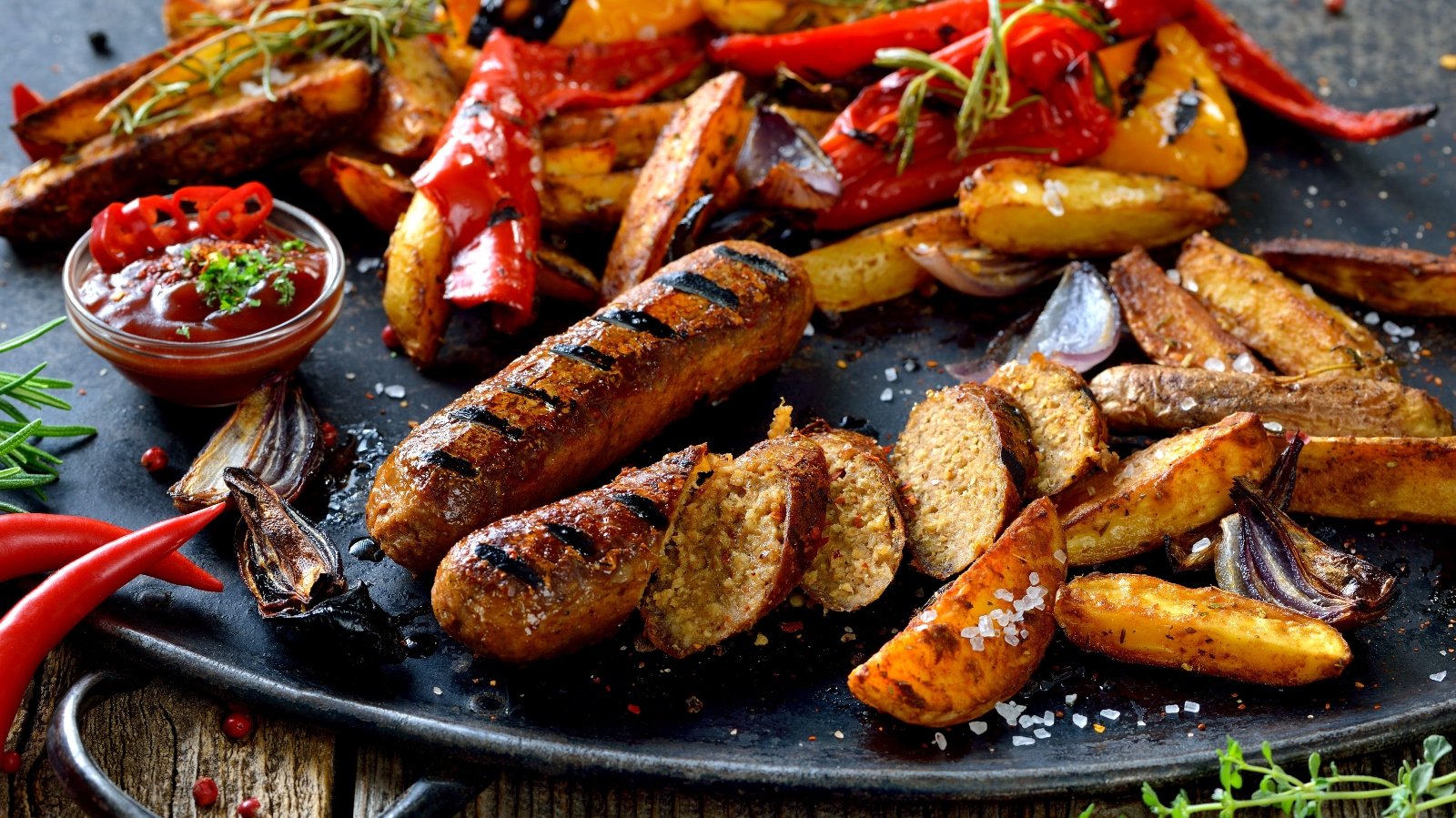 Grilled vegan soy sausages with hot sauce, potato wedges and vegetables
