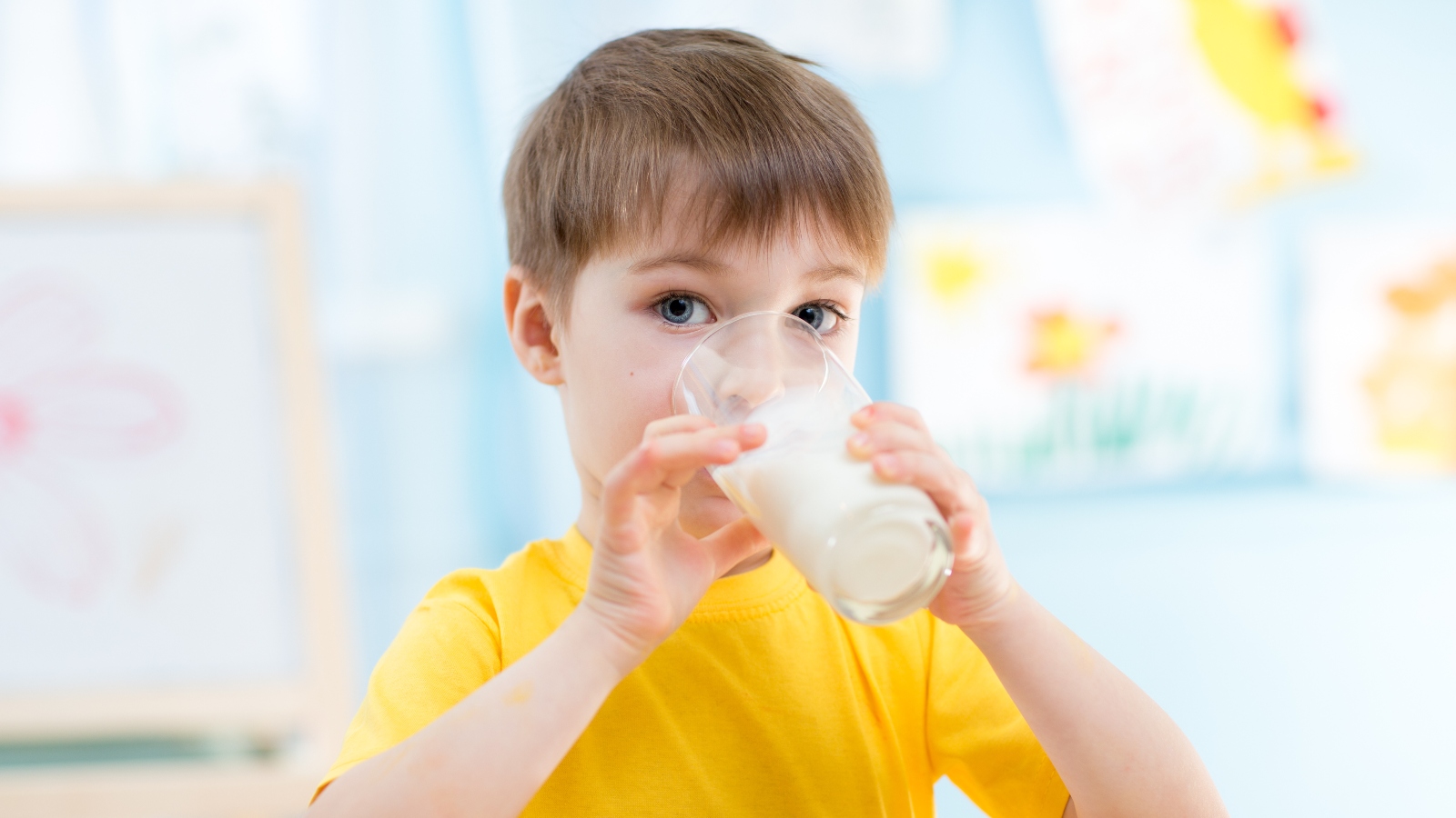 A child wearing a yellow t-shirt drinking milk