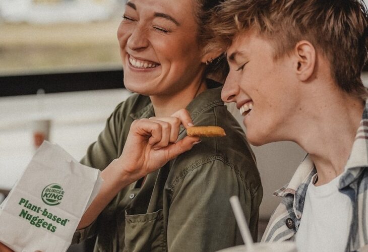 A person laughs while feeding another person plant-based nuggets