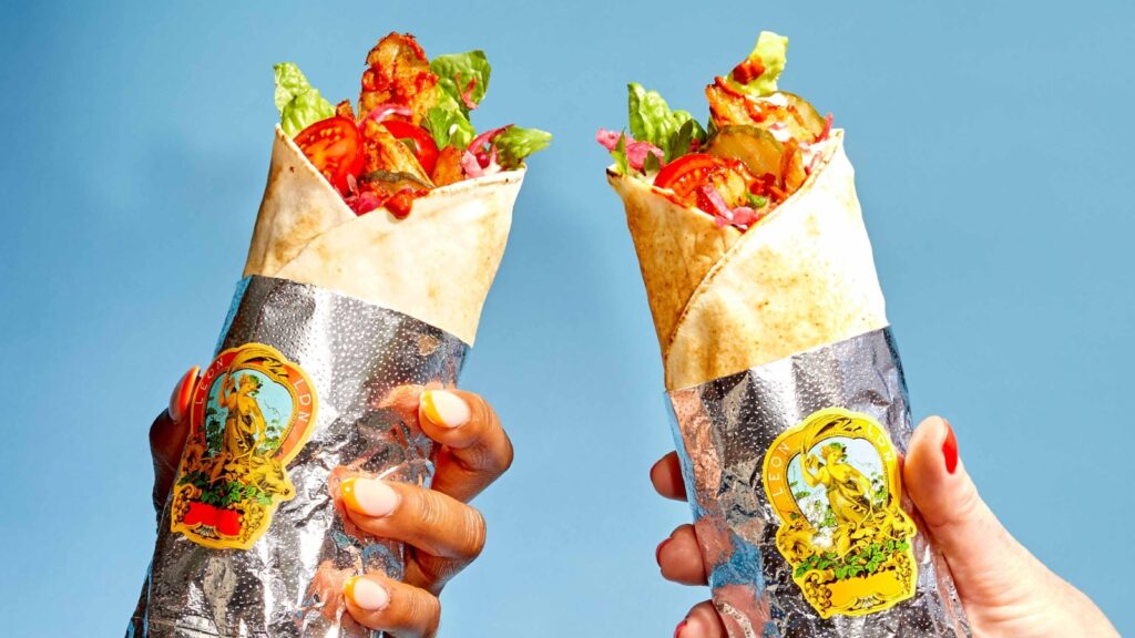 two people hold up vegan chicken wraps