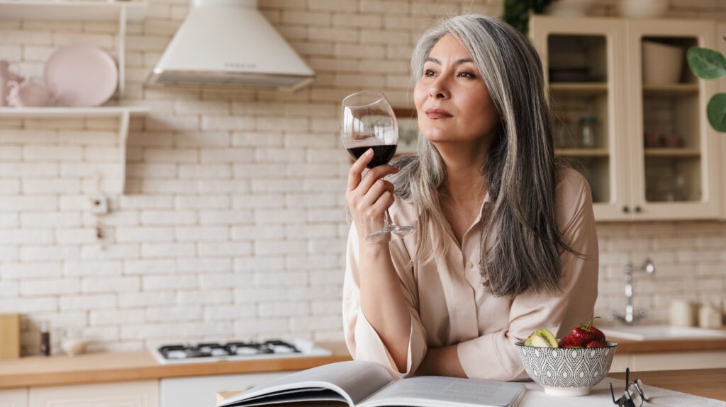 A woman reads in her kitchen drinking wine