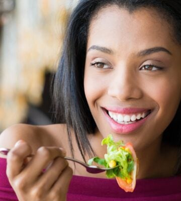 Closeup shot of young woman eating fresh salad at restaurant