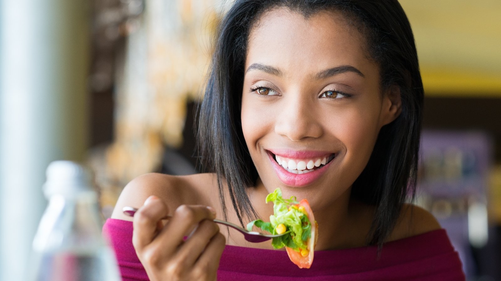 Closeup shot of young woman eating fresh salad at restaurant