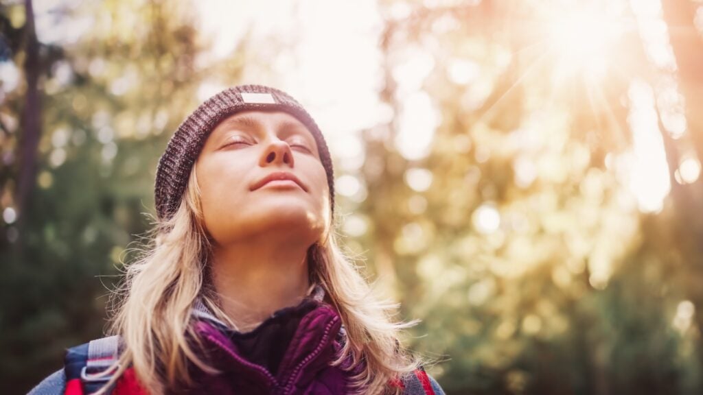 A person with their eyes closed outside in the sun, a vegan source of vitamin D